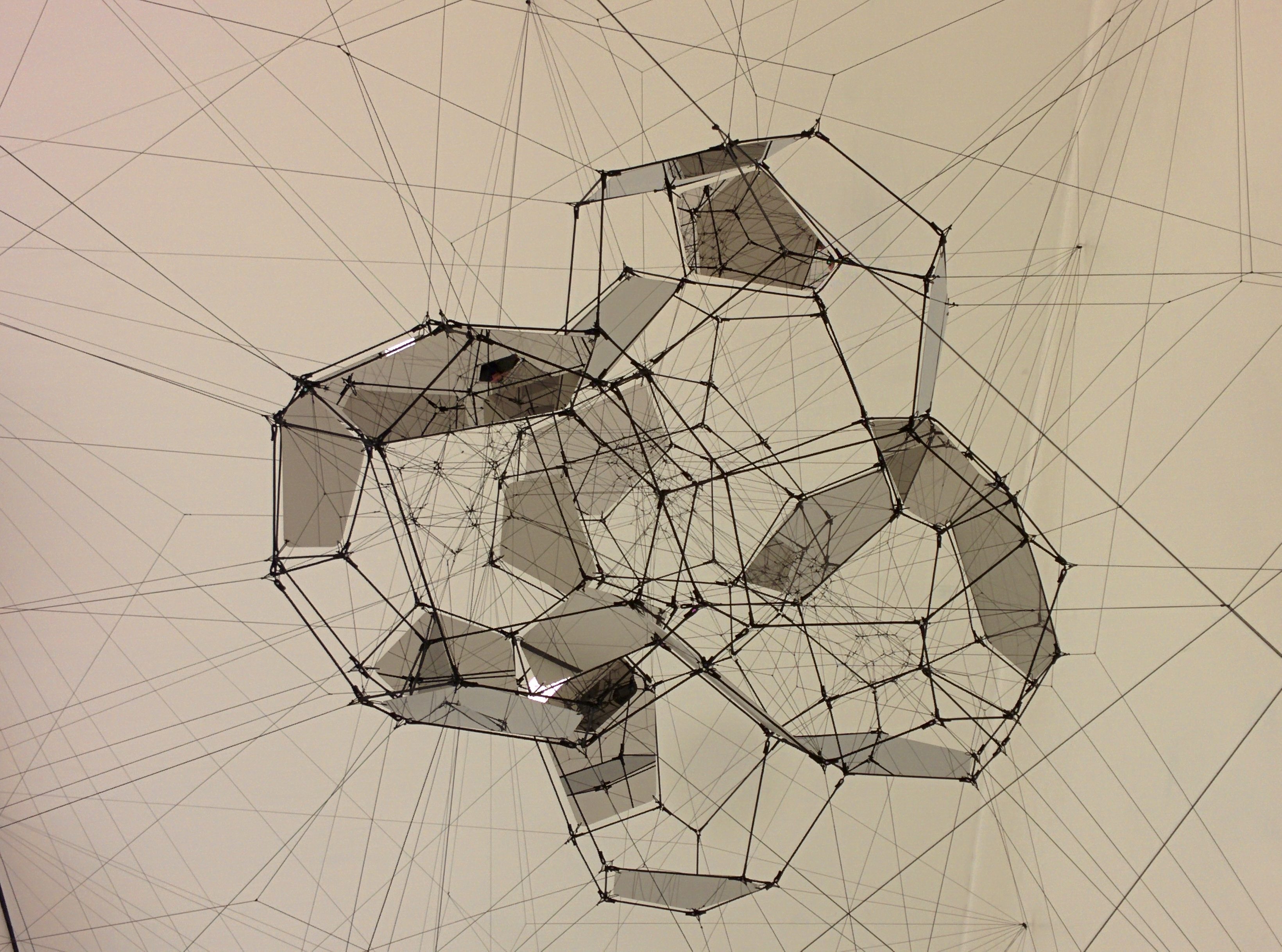 A beige room filled with connected globes made from translucent panels held in place by wires.